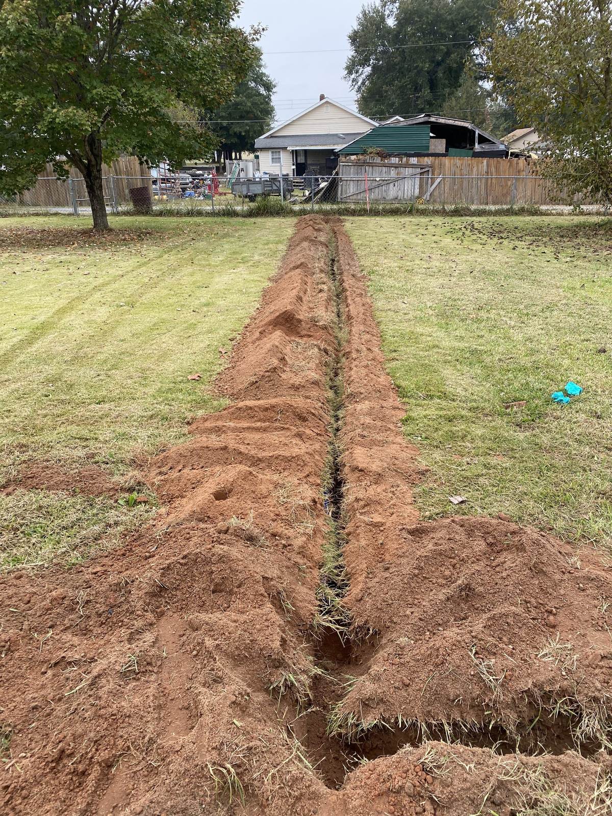 New water service line trenched through red clay to an Upstate home